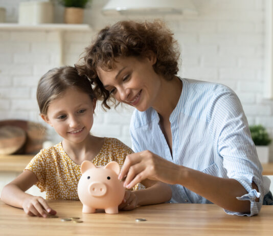 Weltspartag: Die Ergebnisse des Vermögensbarometers Weltspartag: Eine Mutter und ihre Tochter stecken Geld in ein Sparschwein.