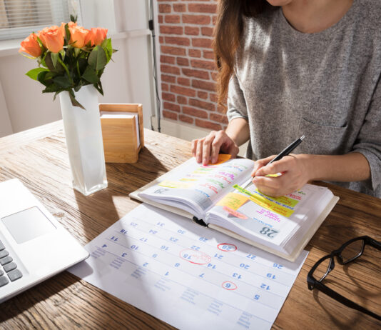 10 Fragen rund um Ihren Urlaub Frau sitzt am Schreibtisch vor einem Terminplaner
