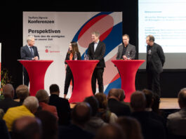 Gestörte Lieferketten: Fachkonferenz in der Förde Sparkasse Eine Frau und vier Männer diskutieren auf einer Bühne vor Publikum