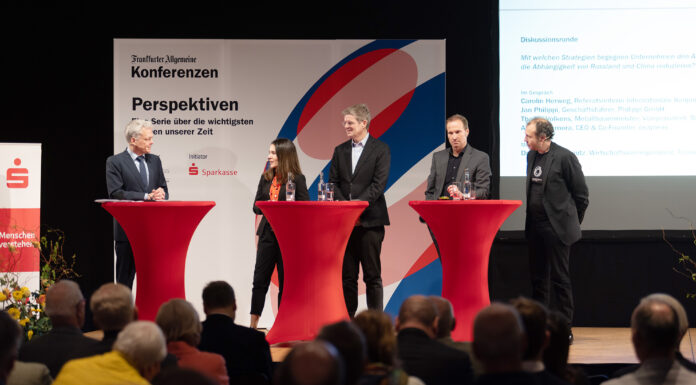 Gestörte Lieferketten: Fachkonferenz in der Förde Sparkasse Eine Frau und vier Männer diskutieren auf einer Bühne vor Publikum