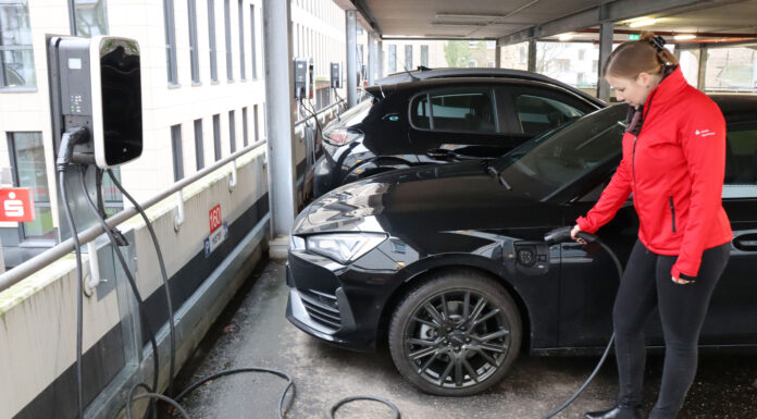 Echt nachhaltig: Förde Sparkasse unterstützt Verkehrswende Eine Mitarbeiterin der Förde Sparkasse lädt ihr E-Auto an einer Ladesäule auf.