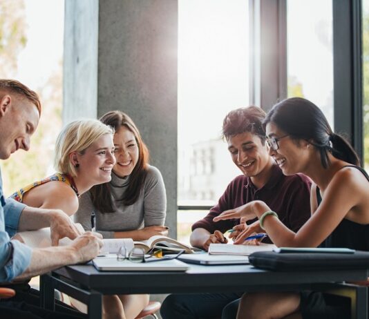 Sparen mit Aktien bei jungen Menschen immer beliebter Junge Studentinnen tauschen sich am Tisch aus.