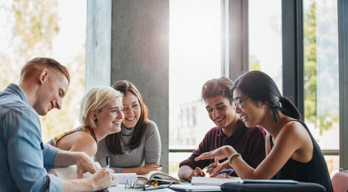 Sparen mit Aktien bei jungen Menschen immer beliebter Junge Studentinnen tauschen sich am Tisch aus.