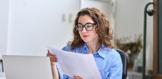 Zinsen, Geldanlage und Inflation – Darum prüfe, wer sich länger bindet Geschäftsfrau prüft Papiere am Computer