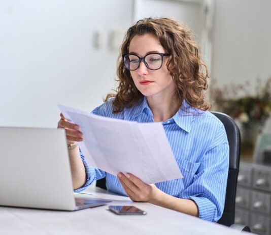 Zinsen, Geldanlage und Inflation – Darum prüfe, wer sich länger bindet Geschäftsfrau prüft Papiere am Computer