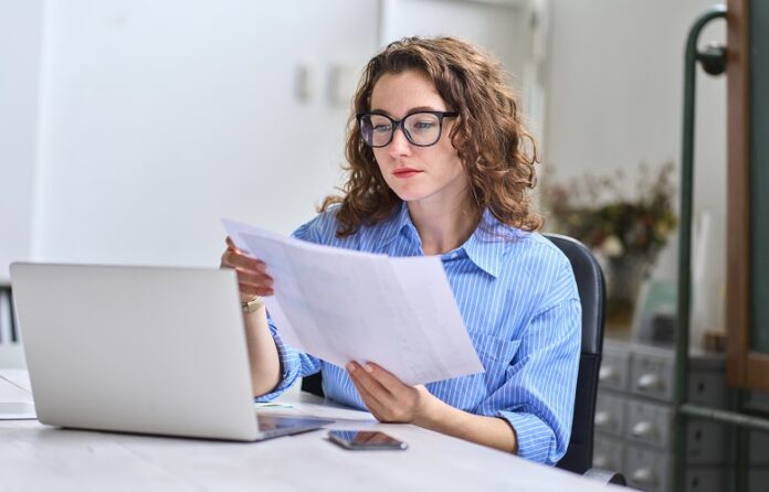 Geschäftsfrau prüft Papiere am Computer
