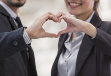 Liebe am Arbeitsplatz Ein Mann und eine Frau formen mit ihren Händen ein Herz