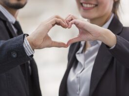 Liebe am Arbeitsplatz Ein Mann und eine Frau formen mit ihren Händen ein Herz