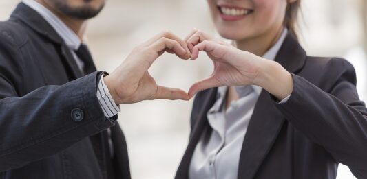 Liebe am Arbeitsplatz Ein Mann und eine Frau formen mit ihren Händen ein Herz