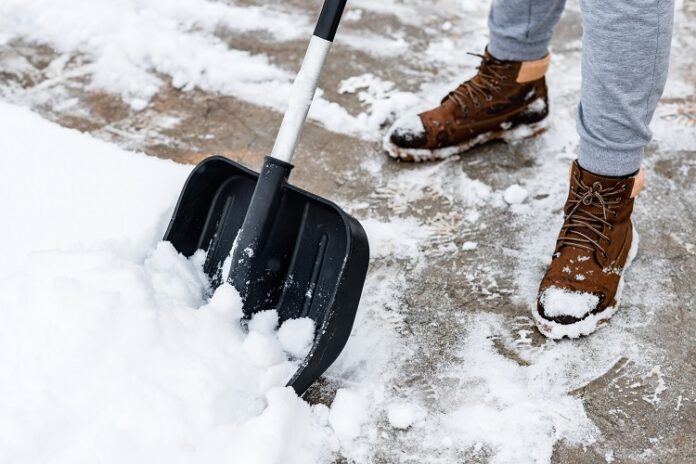 Winterdienstpflicht: Person schippt Schnee vom Gehweg