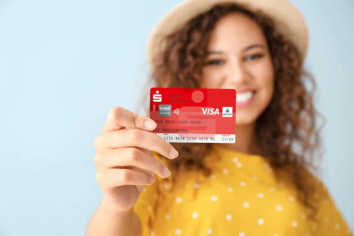 Eine junge Frau hält eine Sparkassen-Card in der Hand.