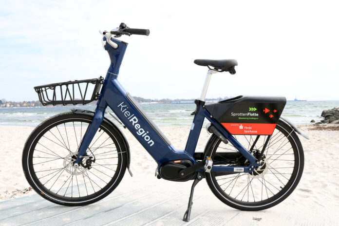 Neues blaues E-Bike der SprotteFlotte am Strand von Eckernförde.