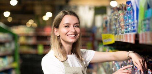 Nebenjob: So können Sie sich Geld dazuverdienen Junge Frau räumt Regale im Supermarkt ein.