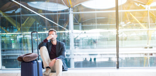 Fluggastrechte: Diese Entschädigungen bekommen Sie Mann sitzt verärgert am Flughafen, weil sein Flug verspätet ist
