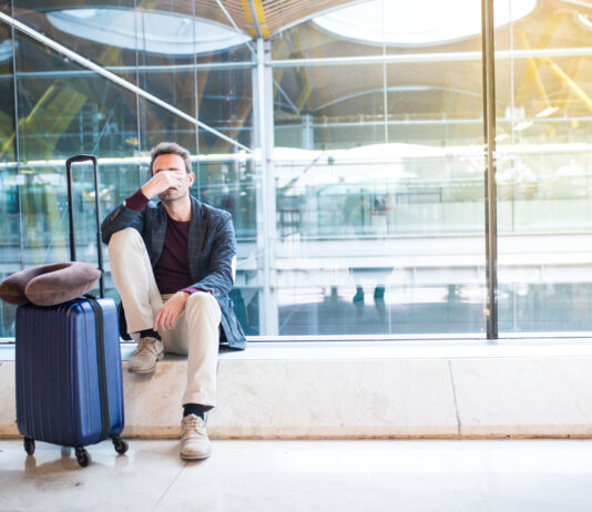 Fluggastrechte: Diese Entschädigungen bekommen Sie Mann sitzt verärgert am Flughafen, weil sein Flug verspätet ist