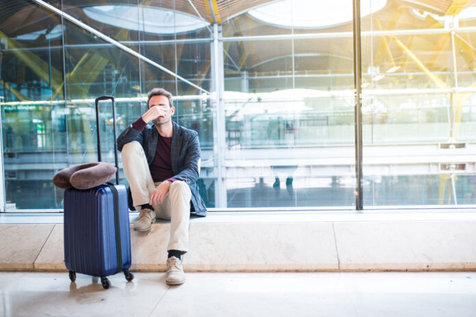 Mann sitzt verärgert am Flughafen, weil sein Flug verspätet ist