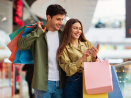 Bonusprogramme in Zeiten von Inflation: Das Instrument zur Kundenbindung und Neukundengewinnung im Einzelhandel Paar beim Shoppen mit Smartphone in der Hand. Bonusprogramm zur Kundenbindung.