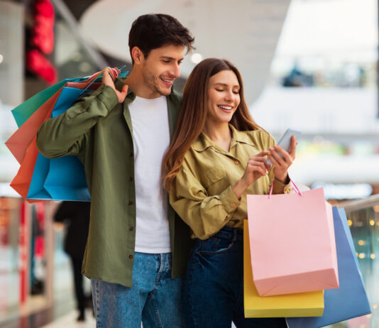 Bonusprogramme in Zeiten von Inflation: Das Instrument zur Kundenbindung und Neukundengewinnung im Einzelhandel Paar beim Shoppen mit Smartphone in der Hand. Bonusprogramm zur Kundenbindung.