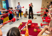 musiculum MOBIL: 60 kostenlose Kita-Einsätze durch die Sparkassen in S-H Eine Frau und viele Kinder blasen in rote Tröten.