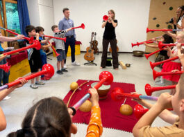 musiculum MOBIL: 60 kostenlose Kita-Einsätze durch die Sparkassen in S-H Eine Frau und viele Kinder blasen in rote Tröten.