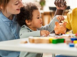 Kindergrundsicherung: Was sich nun ändert Ein Kind steckt eine Münze in ein Sparschwein