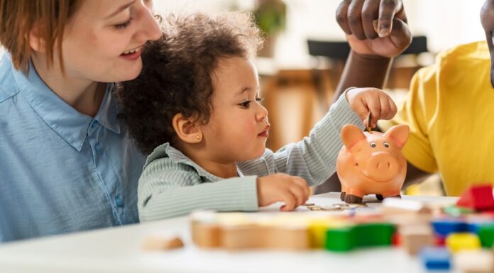 Kindergrundsicherung: Was sich nun ändert Ein Kind steckt eine Münze in ein Sparschwein