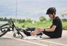 Private Unfallversicherung: Richtig abgesichert bei Freizeitunfällen Junger Radfahrer, der einen Unfall hatte, vom Fahrrad herunterfiel und sein Knie verletzte