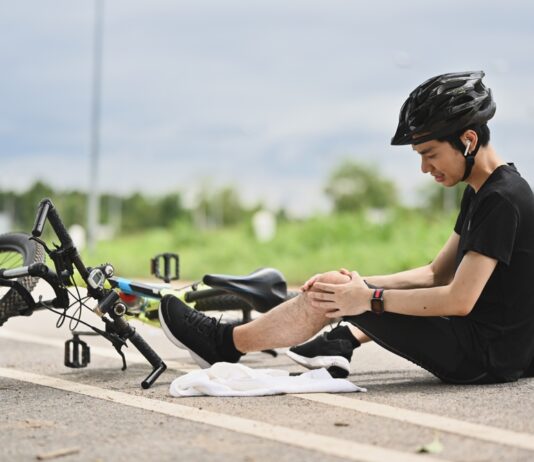 Private Unfallversicherung: Richtig abgesichert bei Freizeitunfällen Junger Radfahrer, der einen Unfall hatte, vom Fahrrad herunterfiel und sein Knie verletzte