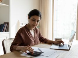 Zinswende und ihre Folgen: Die Rückkehr der Vorabpauschale für Fondsanleger Frau mit Taschenrechner im privaten Büro