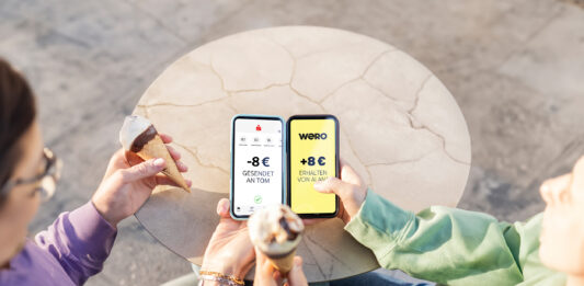Europas neuer Stern am Zahlungshimmel: wero Zwei Menschen sitzen nebeneinander und haben Eistüten in der Hand, sie halten ihre Smartphones nebeneinander und bezahlen mit dem neuen Bezahlsystem wero