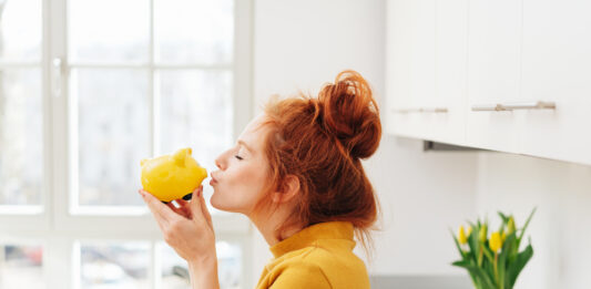 Die 5 besten Spar-Challenges – Kreative Spartipps Rothaarige Frau küsst ein gelbes Sparschwein