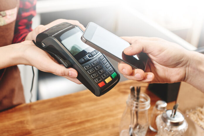 Smartphone wird auf Kartenzahlungsterminal zur Bezahlung gehalten