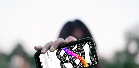 NEU: Förde Sparkasse bei Threads Frau hält Smartphone vor ihr Gesicht, darauf ist die Threads App zu sehen