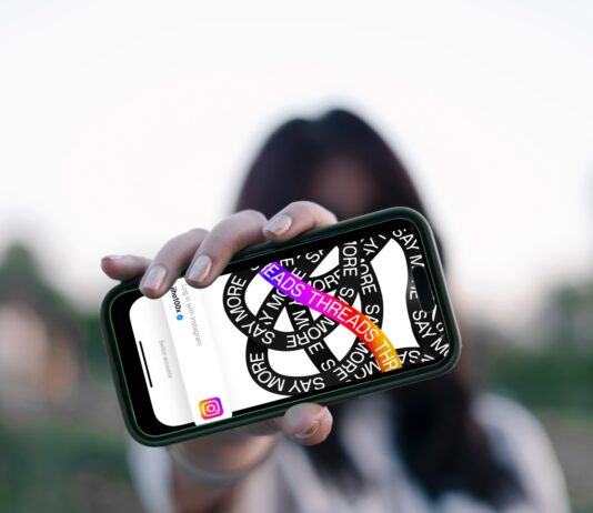 NEU: Förde Sparkasse bei Threads Frau hält Smartphone vor ihr Gesicht, darauf ist die Threads App zu sehen