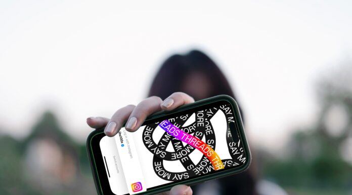 NEU: Förde Sparkasse bei Threads Frau hält Smartphone vor ihr Gesicht, darauf ist die Threads App zu sehen