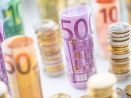 Die Bargeldobergrenze kommt Gestapelte Euromünzen und gerollte Euroscheine