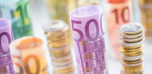 Die Bargeldobergrenze kommt Gestapelte Euromünzen und gerollte Euroscheine