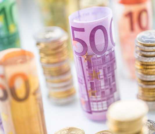 Die Bargeldobergrenze kommt Gestapelte Euromünzen und gerollte Euroscheine