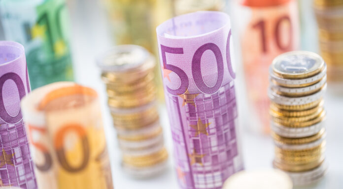 Die Bargeldobergrenze kommt Gestapelte Euromünzen und gerollte Euroscheine