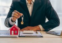 Historisch starker Preisrückgang bei Wohnimmobilien Ein Immobilienmakler hält einen Schlüssel zu einem Haus für seinen Kunden