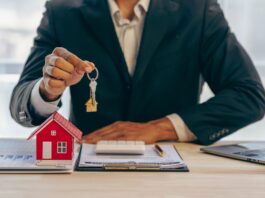 Historisch starker Preisrückgang bei Wohnimmobilien Ein Immobilienmakler hält einen Schlüssel zu einem Haus für seinen Kunden