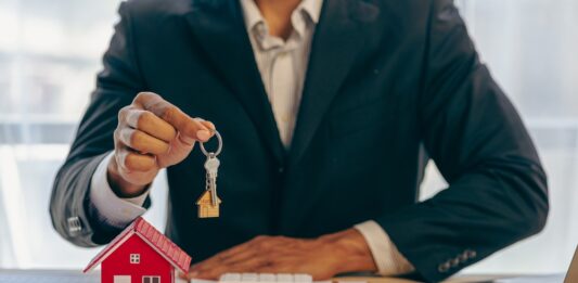 Historisch starker Preisrückgang bei Wohnimmobilien Ein Immobilienmakler hält einen Schlüssel zu einem Haus für seinen Kunden