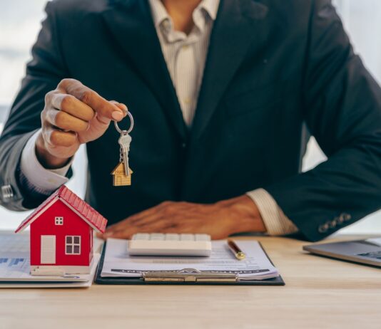 Historisch starker Preisrückgang bei Wohnimmobilien Ein Immobilienmakler hält einen Schlüssel zu einem Haus für seinen Kunden