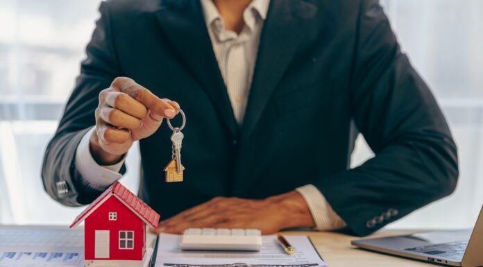 Historisch starker Preisrückgang bei Wohnimmobilien Ein Immobilienmakler hält einen Schlüssel zu einem Haus für seinen Kunden