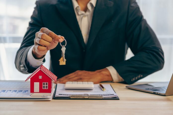 Ein Immobilienmakler hält einen Schlüssel zu einem Haus für seinen Kunden