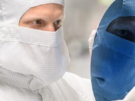 Zins und Dividende im Blick Chiparbeiter schaut auf Chip Waver, Gesicht spiegelt sich blau