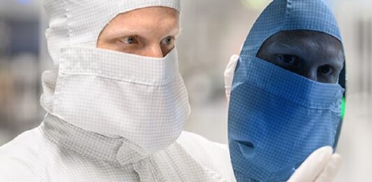 Zins und Dividende im Blick Chiparbeiter schaut auf Chip Waver, Gesicht spiegelt sich blau