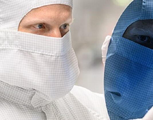 Zins und Dividende im Blick Chiparbeiter schaut auf Chip Waver, Gesicht spiegelt sich blau