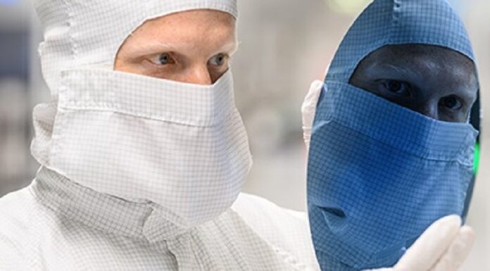 Zins und Dividende im Blick Chiparbeiter schaut auf Chip Waver, Gesicht spiegelt sich blau