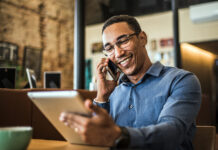 Live-Chat, Social Media, Avatare: Die Vielfalt der digitalen Kundenkommunikation Ein junger POC telefoniert und hat ein Tablet in der Hand.